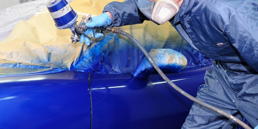 hombre pintando un coche de azul en una cabina